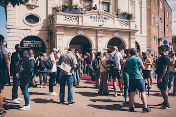 Attendees milling about outside the Duke of York's cinema during a break.