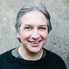 A smiling middle-aged white man with grey hair.